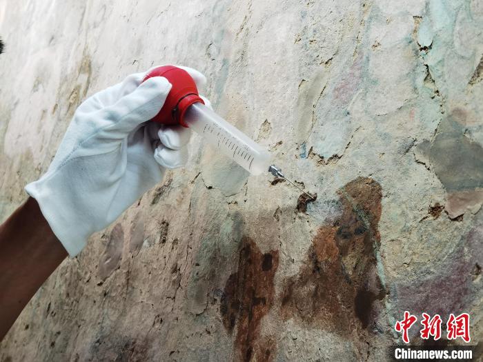 敦煌研究院文物保护技术服务中心的工作人员正在修复壁画。　胡健摄